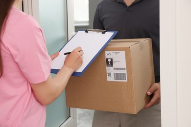 Woman signing for delivered parcel at home, closeup