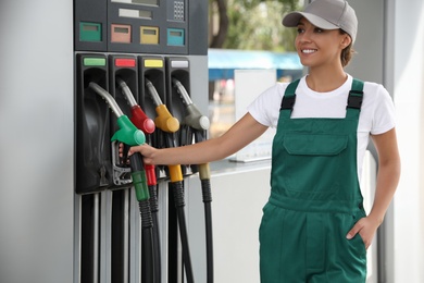 Worker taking fuel pump nozzle at modern gas station
