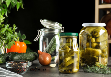 Glass jars of pickled cucumbers on grey table