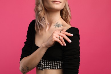 Photo of Beautiful woman with tattoos on body against pink background, closeup
