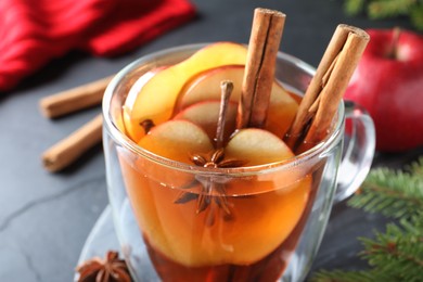 Aromatic hot mulled cider on black table, closeup