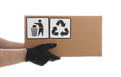 Courier holding cardboard box with different packaging symbols on white background, closeup. Parcel delivery