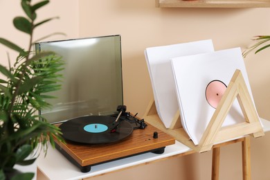 Stylish turntable with vinyl record on wooden table in room