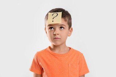 Emotional little boy with question mark on white background