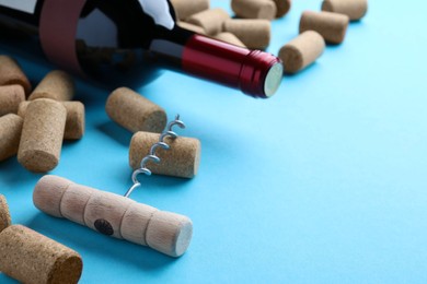 Corkscrew with wine bottle and stoppers on turquoise background