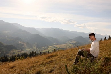 Photo of Man working with laptop outdoors surrounded by beautiful nature. Space for text