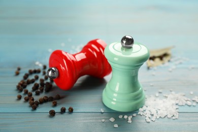 Salt and pepper shakers on turquoise wooden table, closeup. Spice mill