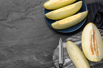 Pieces of delicious honeydew melon on black slate table, flat lay. Space for text