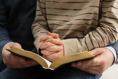 Boy and his godparent reading Bible together, closeup