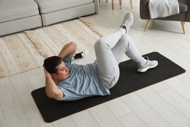 Overweight man doing abs exercise on mat at home