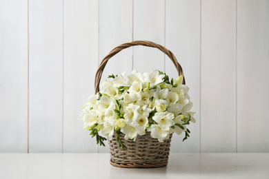 Beautiful freesia flowers in basket on white table