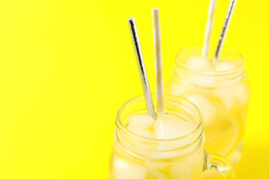 Closeup view of natural lemonade on yellow background, space for text. Summer refreshing drink