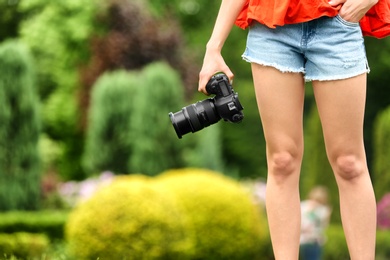 Photo of Photographer with professional camera in park, closeup. Space for text