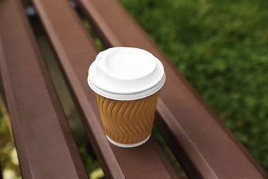 Paper cup on wooden bench outdoors. Coffee to go