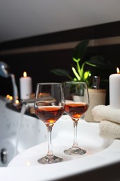 Bathtub with glasses of wine and candles indoors. Romantic atmosphere