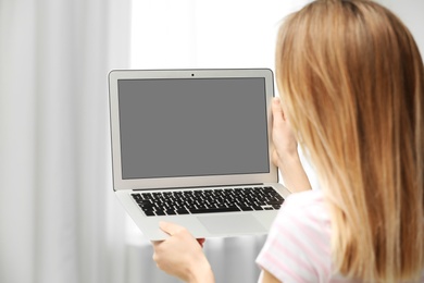 Young woman using video chat on laptop indoors, closeup. Space for design
