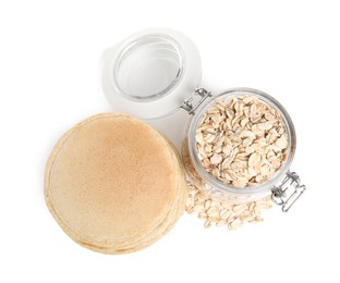Tasty oatmeal pancakes and flakes on white background, top view