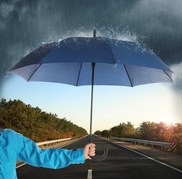 Woman with open blue umbrella on empty asphalt road, closeup