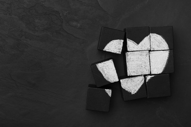 Heart drawn on black cubes, flat lay with space for text. Composition symbolizing problems in relationship
