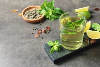 Glass with hot aromatic mint tea, fresh leaves and lime on table