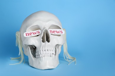 Photo of Information and media warfare concept. Human skull with noodles and words News in eye sockets on light blue background, space for text