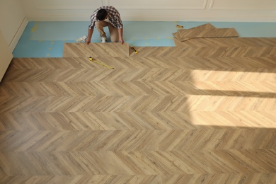 Professional worker installing new parquet flooring indoors, above view