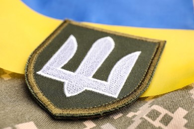 Photo of Military patch and Ukrainian flag on pixel camouflage, closeup