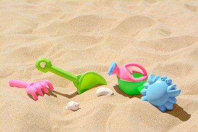 Photo of Bright plastic rake and shovel on sand. Beach toys. Space for text