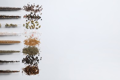 Test tubes with various spices on white background, flat lay. Space for text