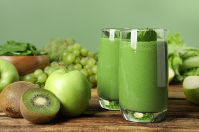 Green smoothie in glasses and fresh ingredients on wooden table