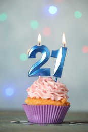 21th birthday. Delicious cupcake with number shaped candles for coming of age party on light blue table