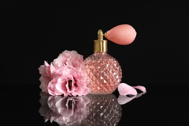 Photo of Vintage bottle of perfume and beautiful flowers on black background