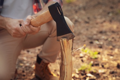 Man chopping firewood with axe in forest, closeup