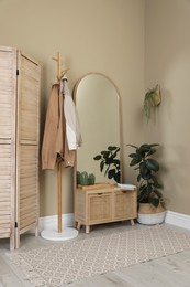 Stylish hallway room interior with wooden commode, coat rack and large mirror