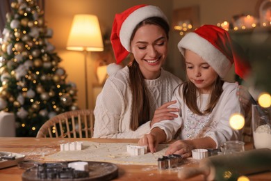 Mother with her cute little daughter making Christmas cookies in kitchen