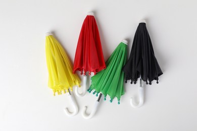 Small color umbrellas on white background, top view