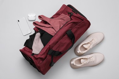 Gym bag and sports equipment on light grey background, flat lay