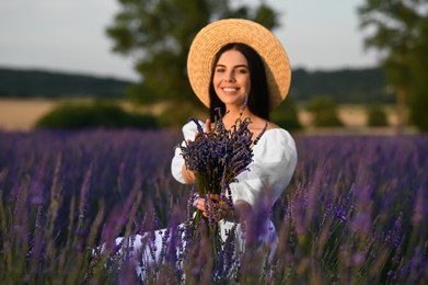 Beautiful young woman with bouquet sitting in lavender field