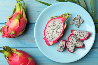 Plate with delicious cut and whole white pitahaya fruits on light blue wooden table, flat lay