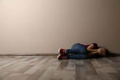 Photo of Little girl closing her eyes on floor indoors, space for text. Child in danger