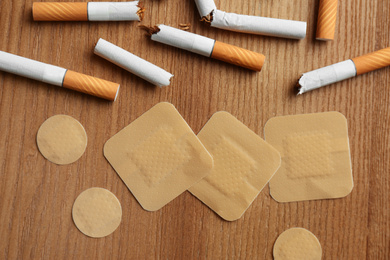 Nicotine patches and broken cigarettes on wooden table, flat lay