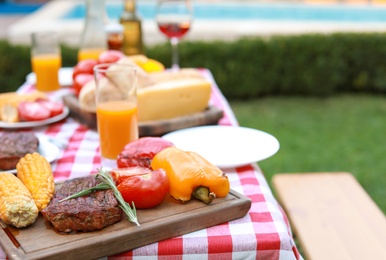 Table with delicious food and drinks outdoors, closeup. Barbecue party
