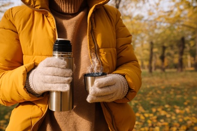 Woman with thermos outdoors, closeup. Space for text