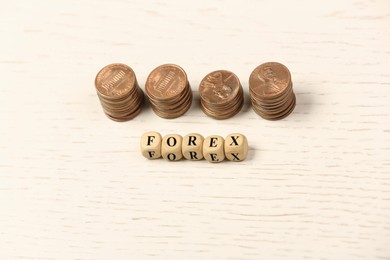 Word Forex with cubes and stacked coins on white wooden table, above view