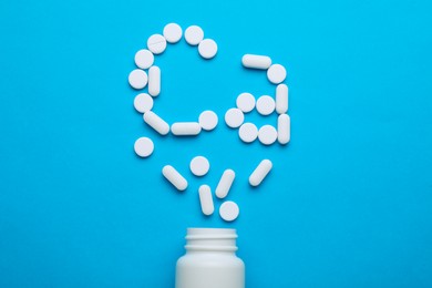 Open bottle and calcium symbol made of white pills on light blue background, flat lay