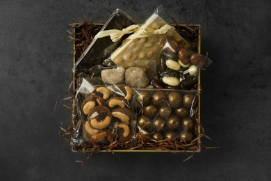 Box with chocolate and sweets on dark grey table, top view