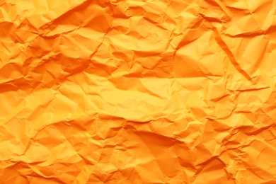 Texture of orange crumpled paper as background, closeup