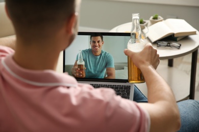Friends drinking beer while communicating through online video conference at home. Social distancing during coronavirus pandemic