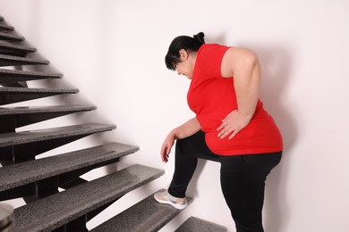 Overweight mature woman suffering from pain in left side while running upstairs indoors