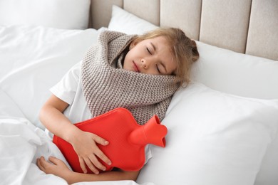 Ill girl with hot water bottle suffering from cold in bed at home
